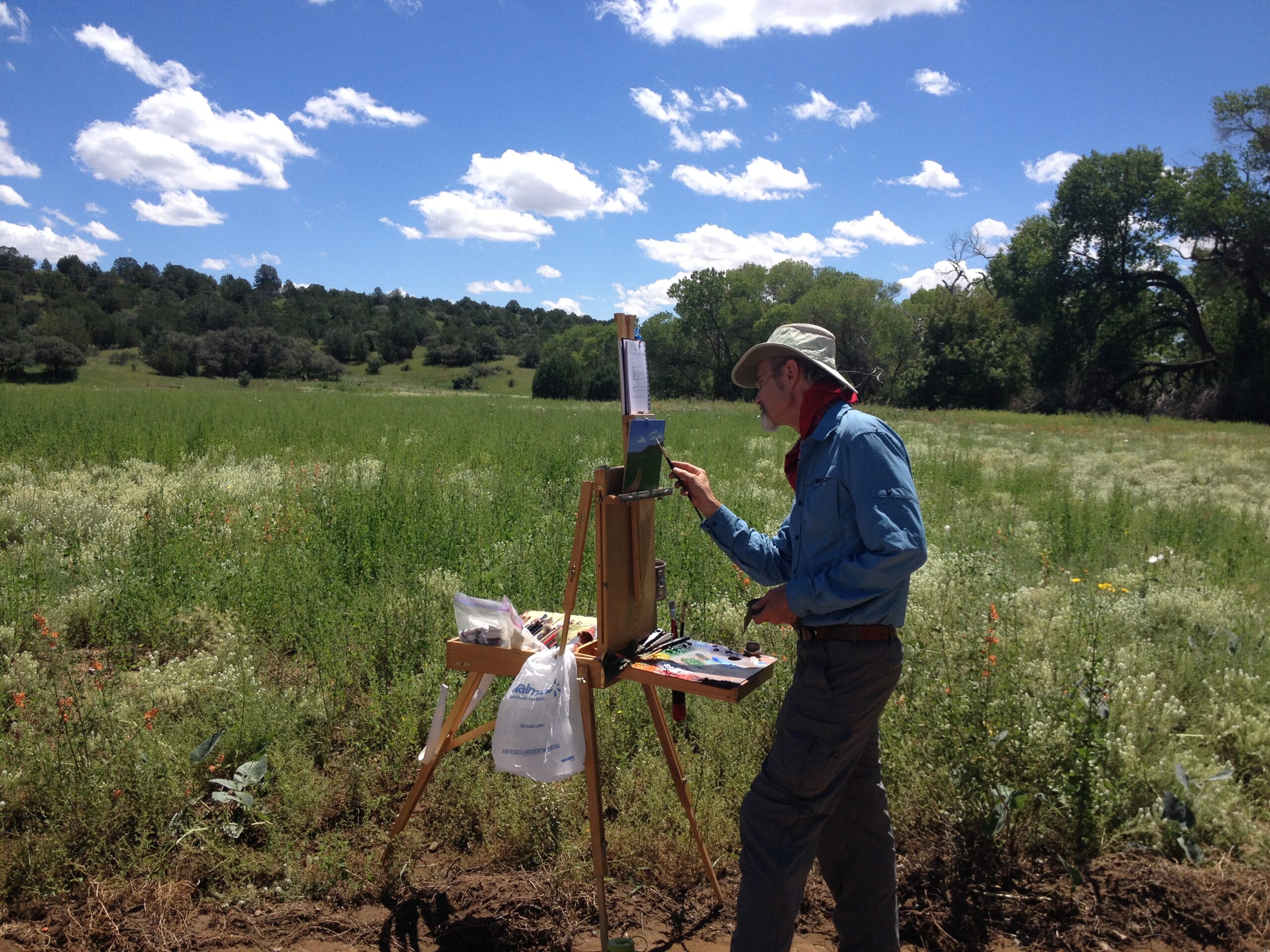 Artist Pete Farrow painting en plein air in a desert field.